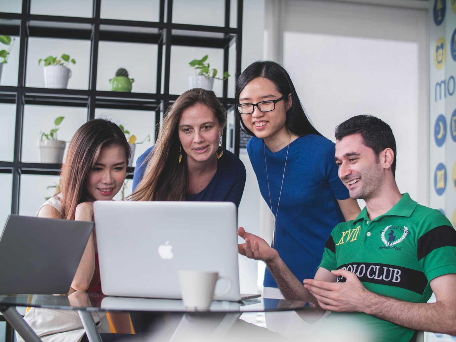 A counsellor going through university options with three students at a laptop